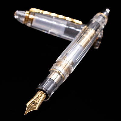  Nagasawa Original Standard Fountain Pen - Skeleton Proske Gold laying across its own cap, crossed, with a focus on the nib.