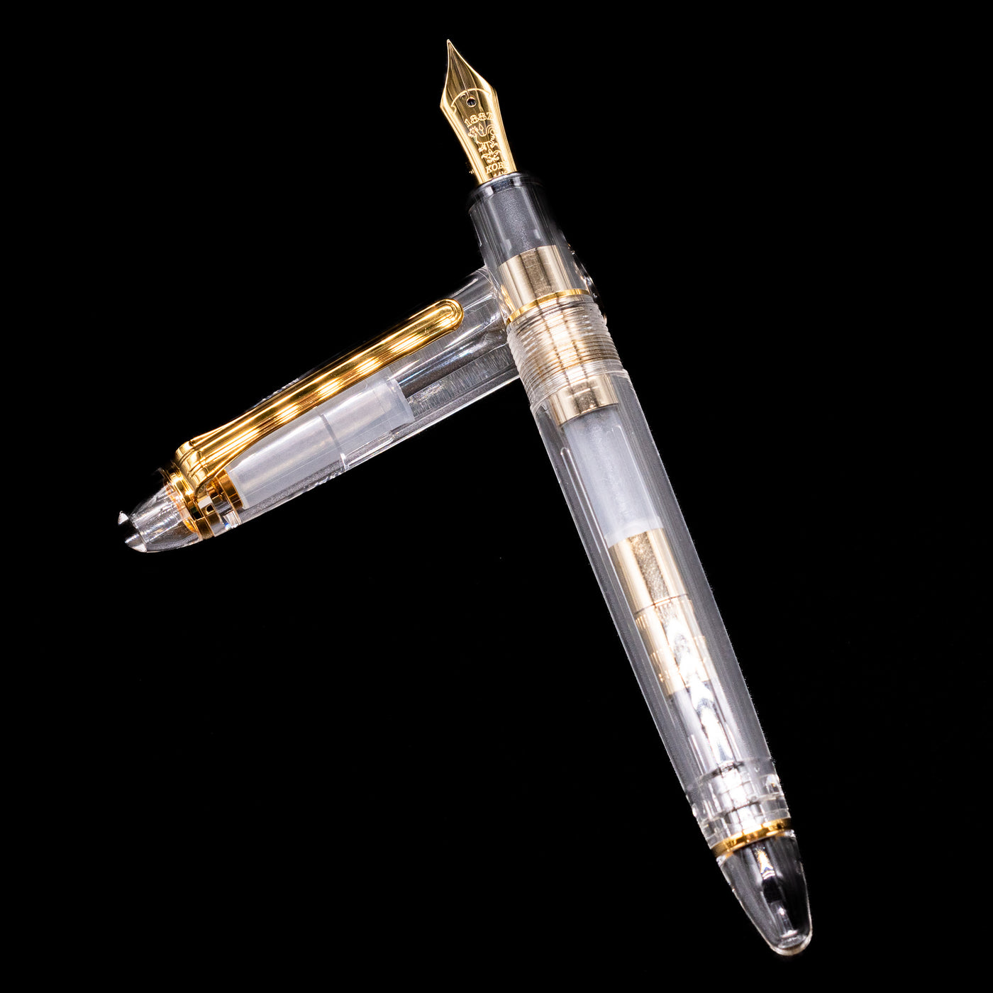 Nagasawa Original Standard Fountain Pen - Skeleton Proske Gold laying on top of its cap in a crossed position showing full view of the entire uncapped pen.