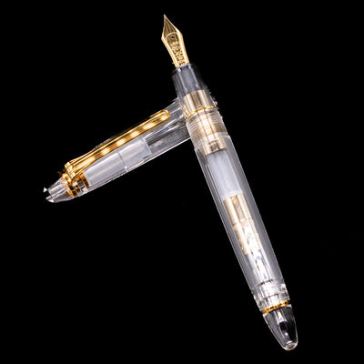 Nagasawa Original Standard Fountain Pen - Skeleton Proske Gold laying on top of its cap in a crossed position showing full view of the entire uncapped pen.