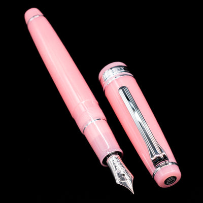  A full view of the Nagasawa Original Standard Onomatopoeia Fountain Pen - Doki Doki uncapped, with its cap laying next to the pen. 