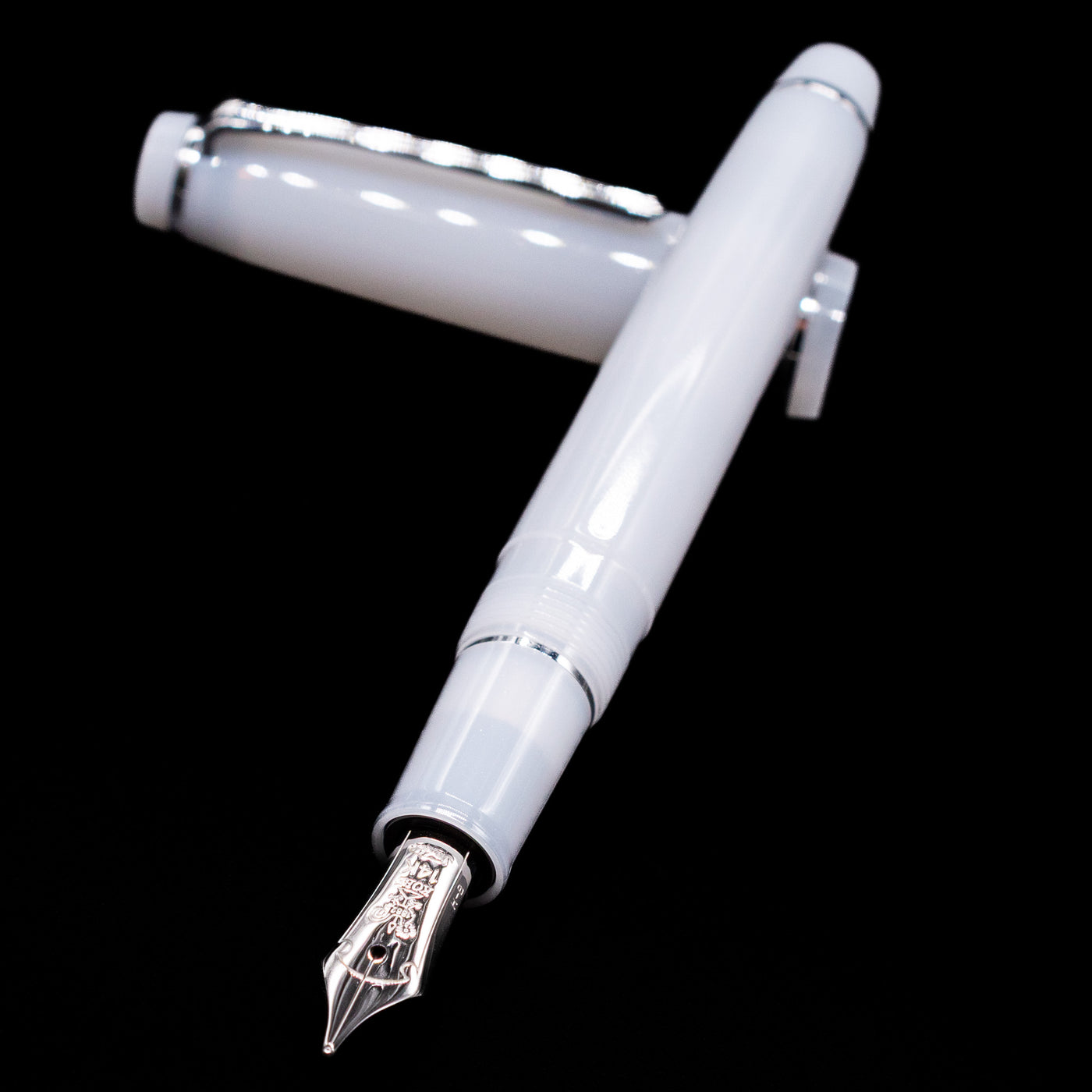 Nagasawa Original Standard Onomatopoeia Fountain Pen - Kasya Kasya laying across its own cap, crossed, with a focus on the nib.