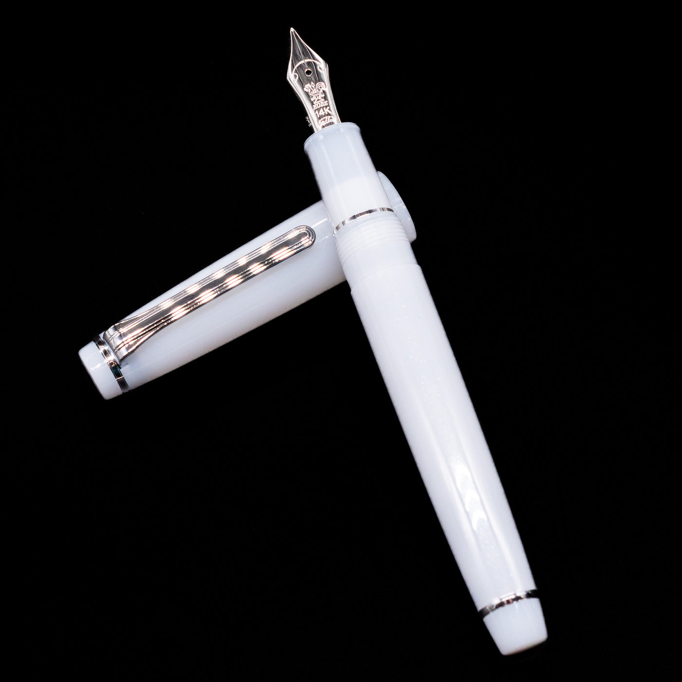 Nagasawa Original Standard Onomatopoeia Fountain Pen - Kasya Kasya laying on top of its cap in a crossed position showing full view of the entire uncapped pen.