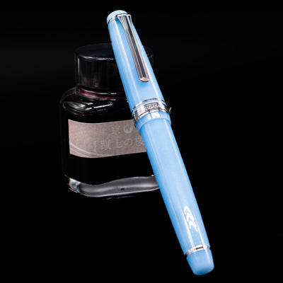 Nagasawa Original Standard Onomatopoeia Fountain Pen - Puka Puka capped, leaning against an ink bottle. 