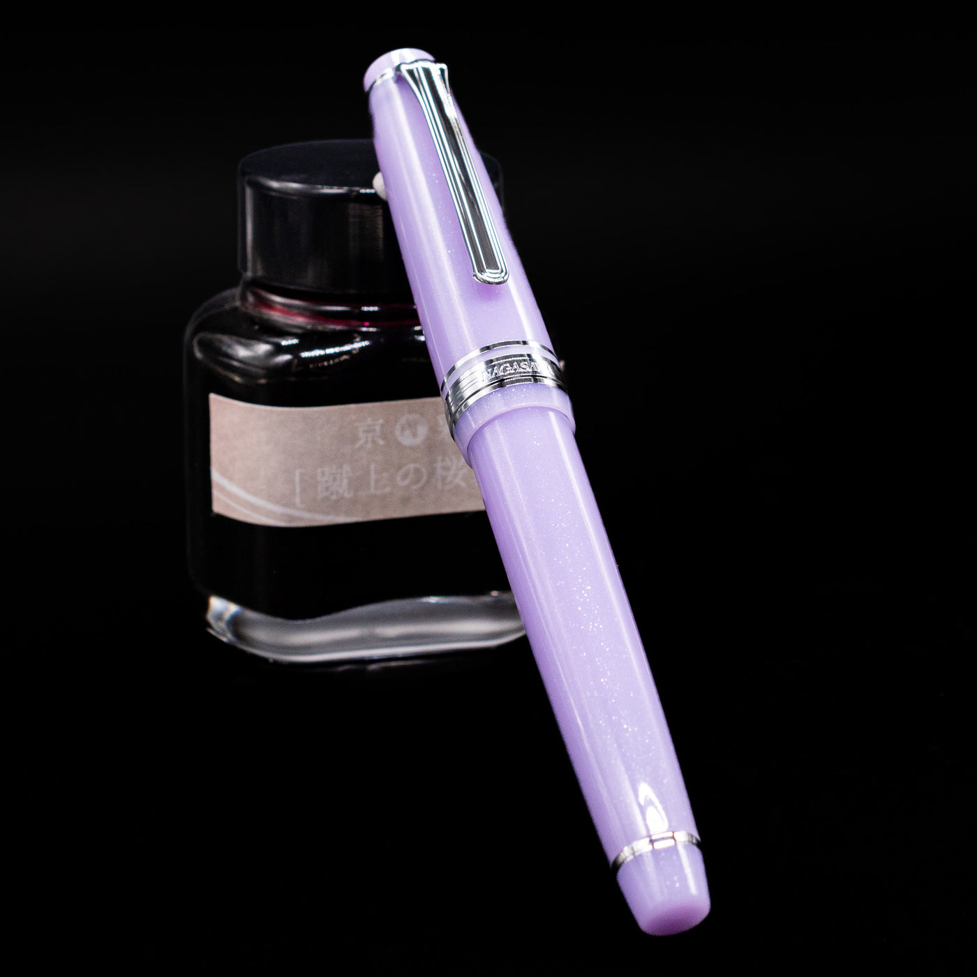 Nagasawa Original Standard Onomatopoeia Fountain Pen - Yura Yura capped, leaning against an ink bottle. 