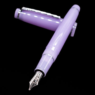 Nagasawa Original Standard Onomatopoeia Fountain Pen - Yura Yura laying across its own cap, crossed, with a focus on the nib.