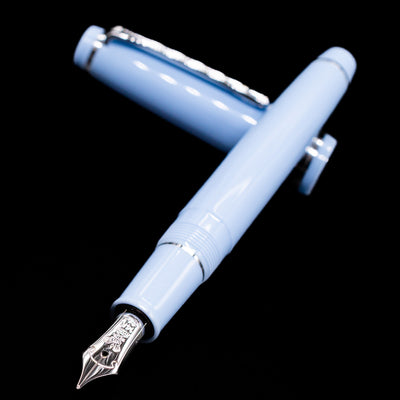 Nagasawa Original Standard Rokko Fountain Pen - Island Sky laying across its own cap, crossed, with a focus on the nib.