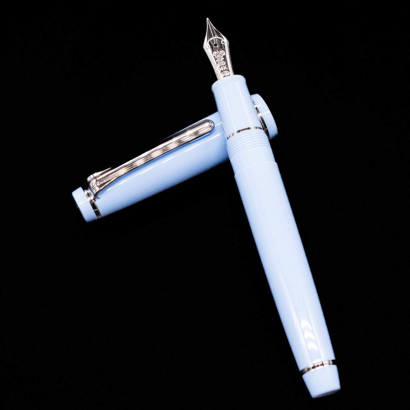 Nagasawa Original Standard Rokko Fountain Pen - Island Sky laying on top of its cap in a crossed position showing full view of the entire uncapped pen.