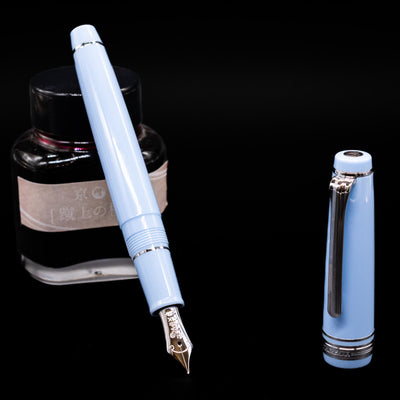 Nagasawa Original Standard Rokko Fountain Pen - Island Sky leaning on an ink bottle uncapped showcasing the detailing on the nib.