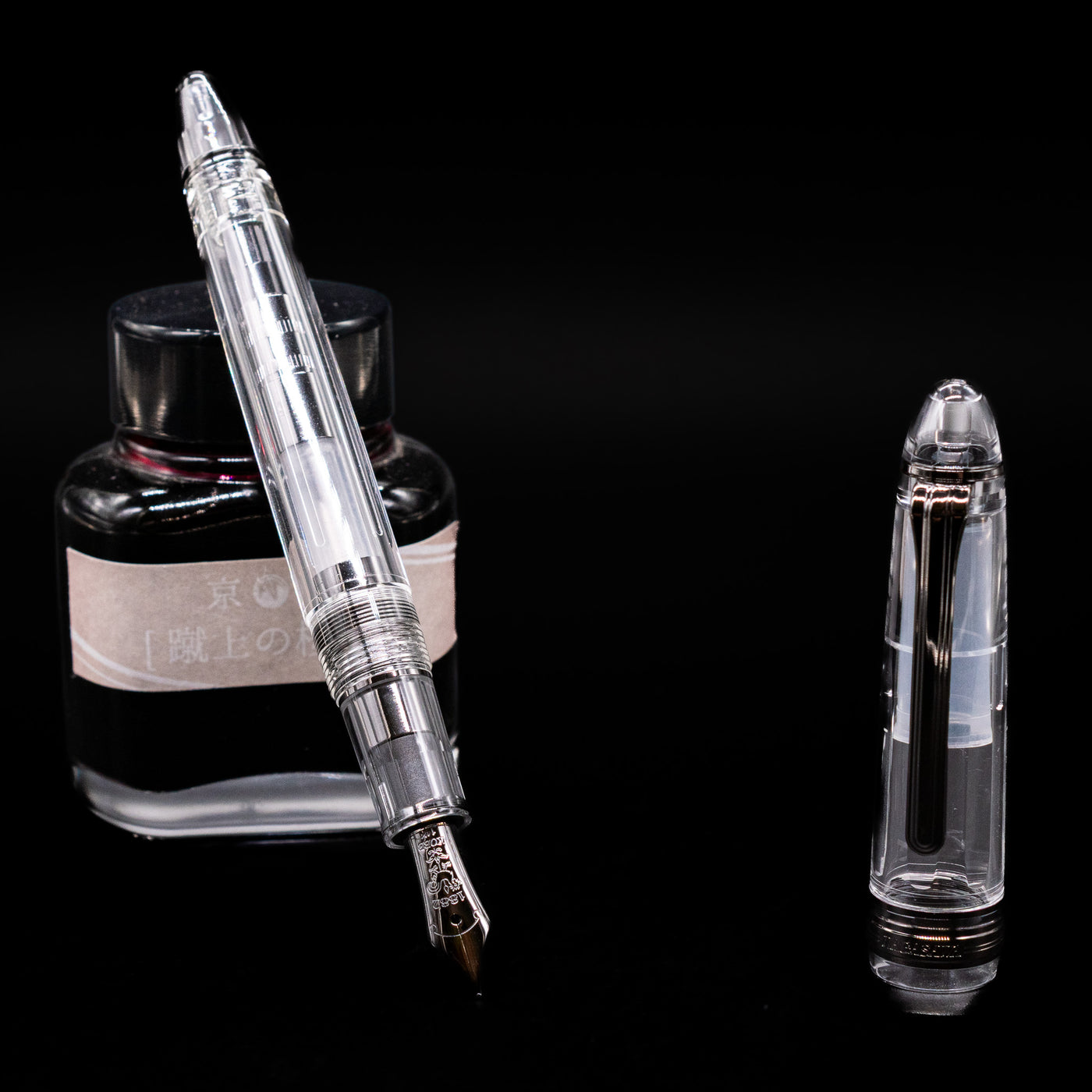 Nagasawa Original Standard Fountain Pen - Skeleton Proske Black leaning on an ink bottle uncapped showcasing the detailing on the nib.