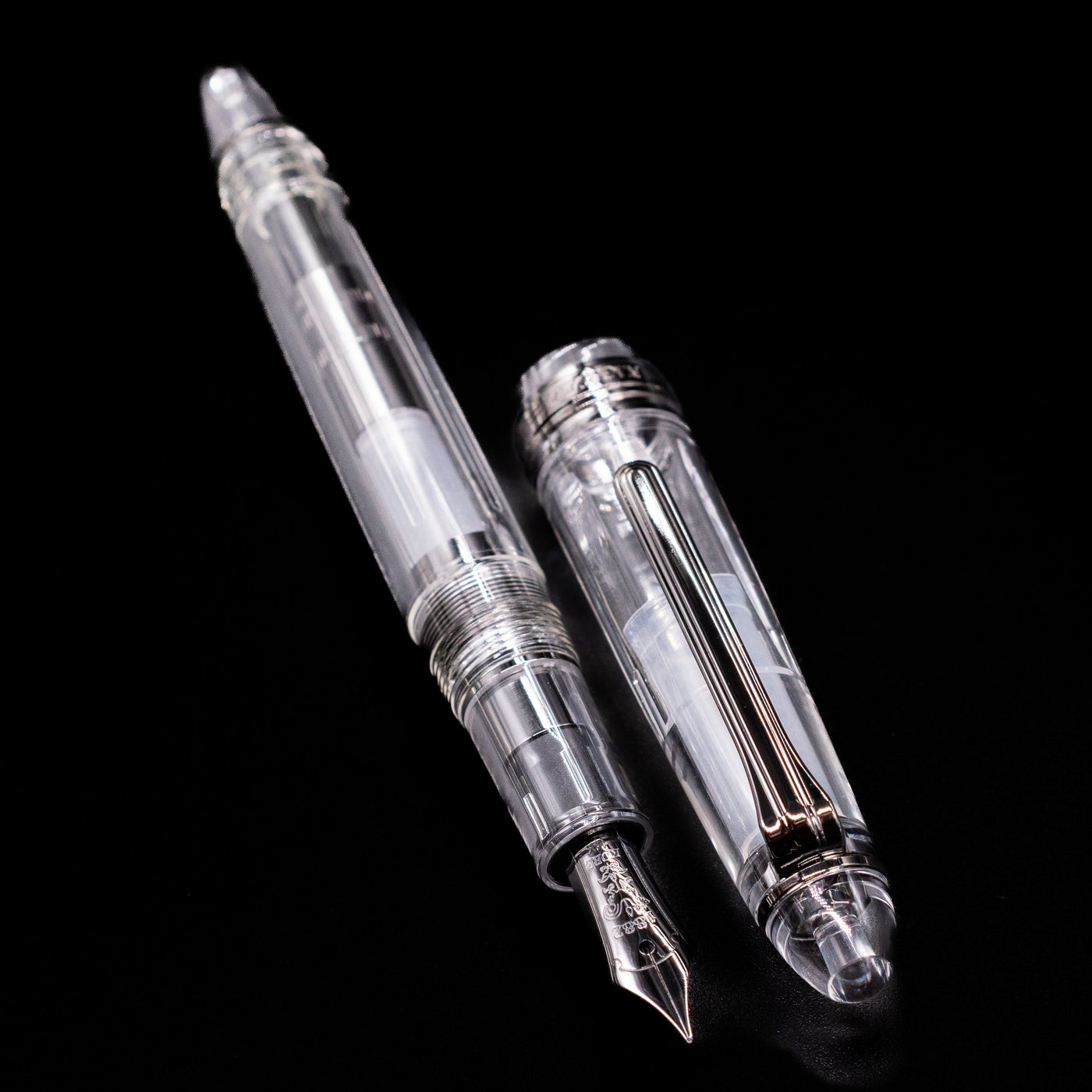 A full view of the Nagasawa Original Standard Fountain Pen - Skeleton Proske Black  uncapped, with its cap laying next to the pen. 