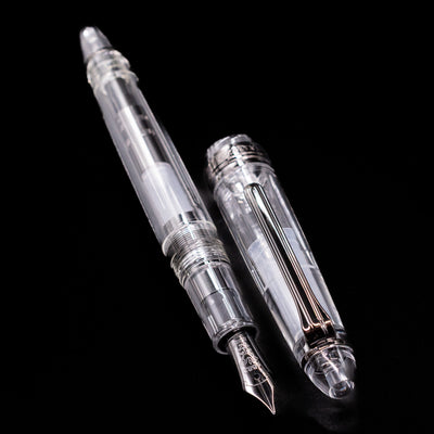 A full view of the Nagasawa Original Standard Fountain Pen - Skeleton Proske Black  uncapped, with its cap laying next to the pen. 