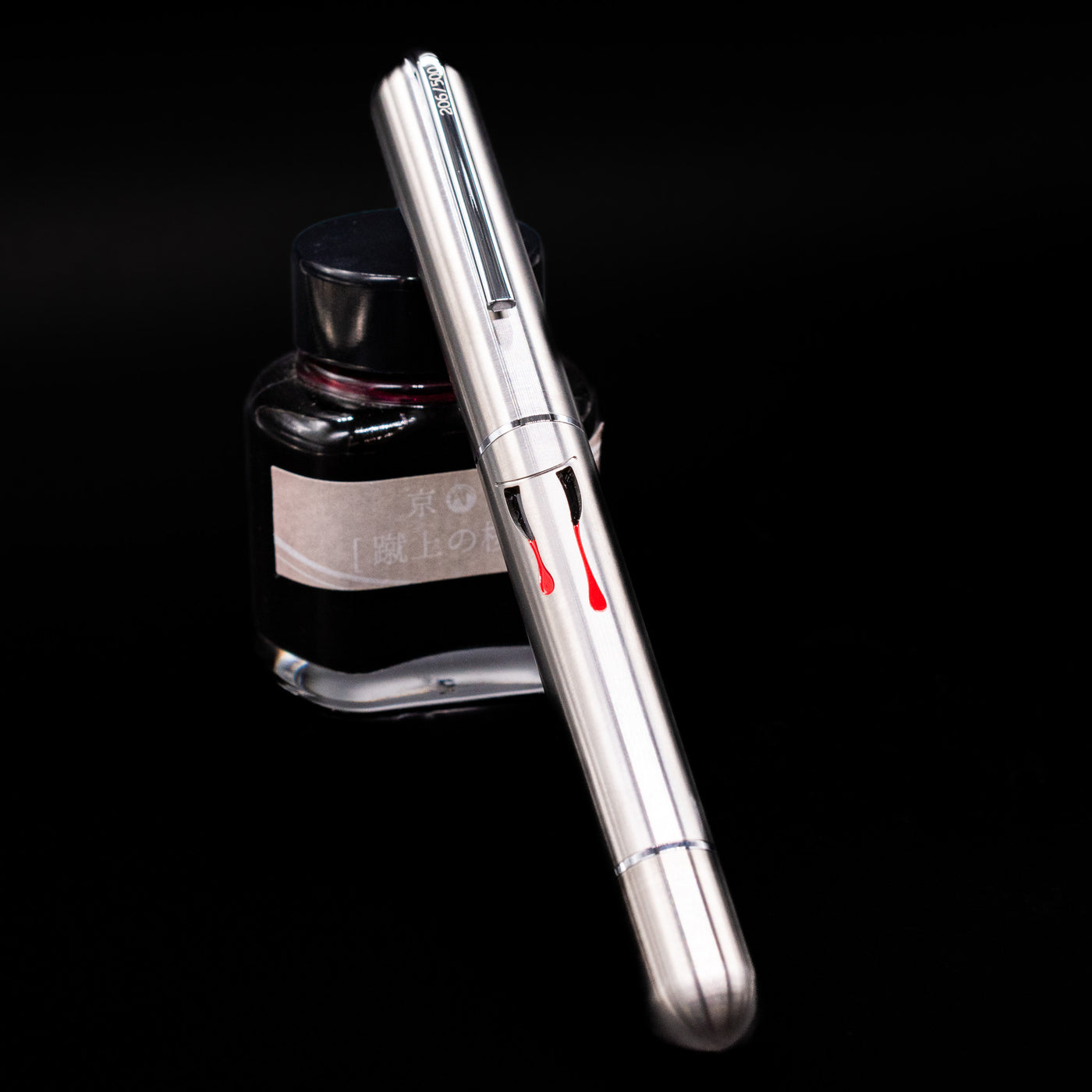 Nahvalur Dracula Fountain Pen capped, leaning against an ink bottle.