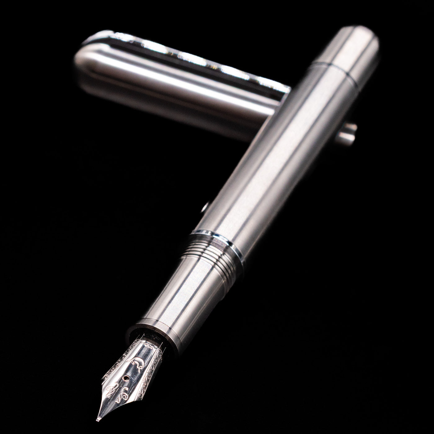 Nahvalur Dracula Fountain Pen laying across its own cap, crossed, with a focus on the nib.