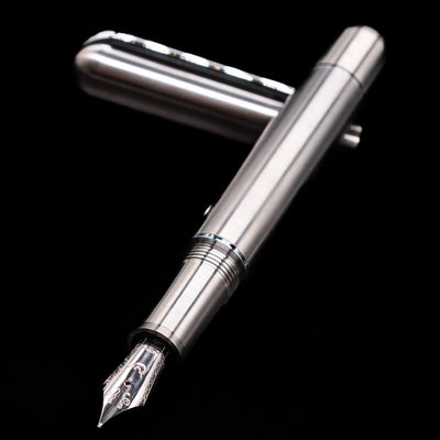 Nahvalur Dracula Fountain Pen laying across its own cap, crossed, with a focus on the nib.