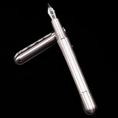 Nahvalur Dracula Fountain Pen laying on top of its cap in a crossed position showing full view of the entire uncapped pen.