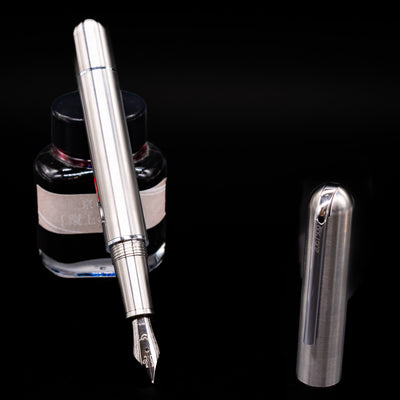 Nahvalur Dracula Fountain Pen leaning on an ink bottle uncapped showcasing the detailing on the nib.