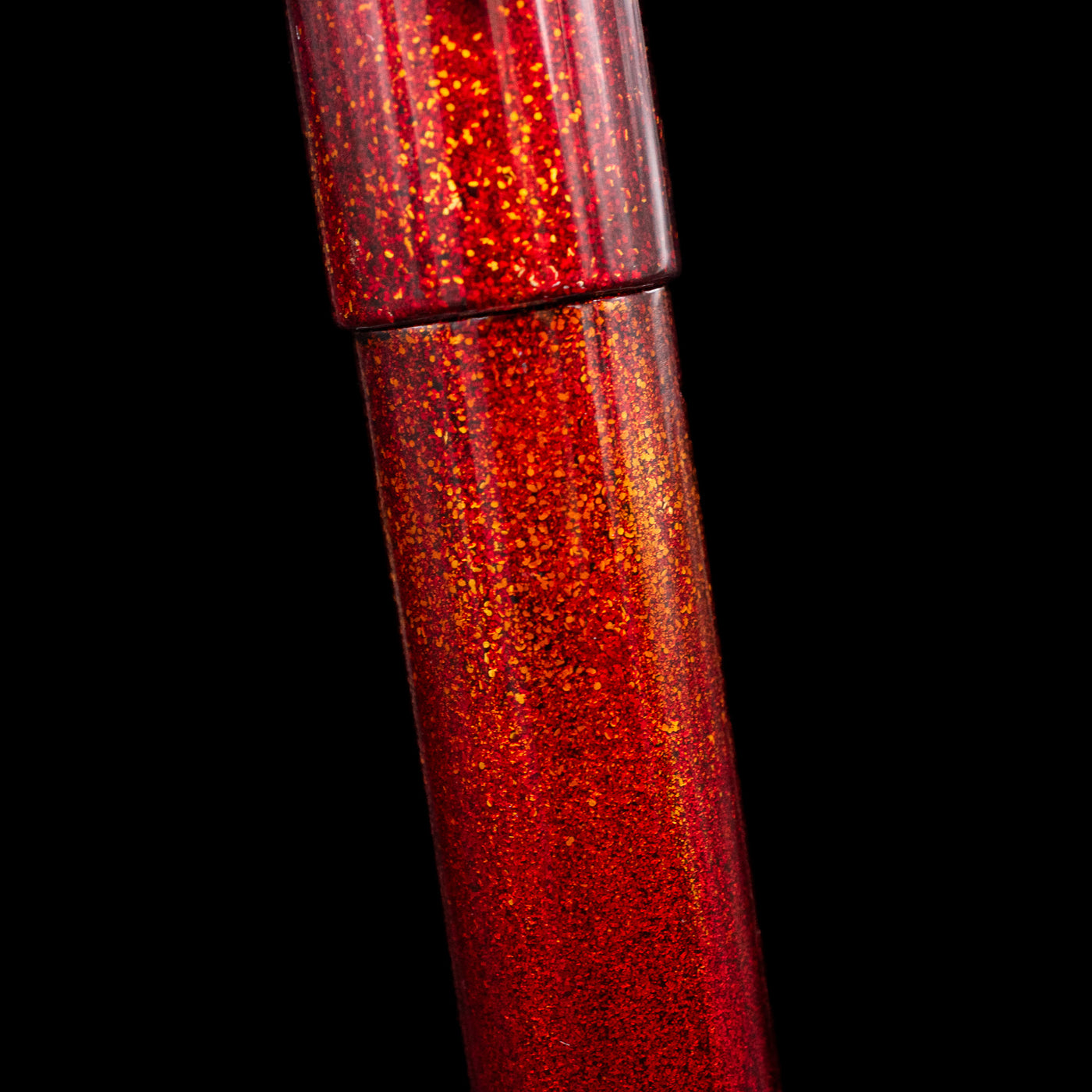 A close-up view of the body of the Nahvalur Ikkaku Urushi Fountain Pen - Blood Moon showcasing the colorful sparkle details. 