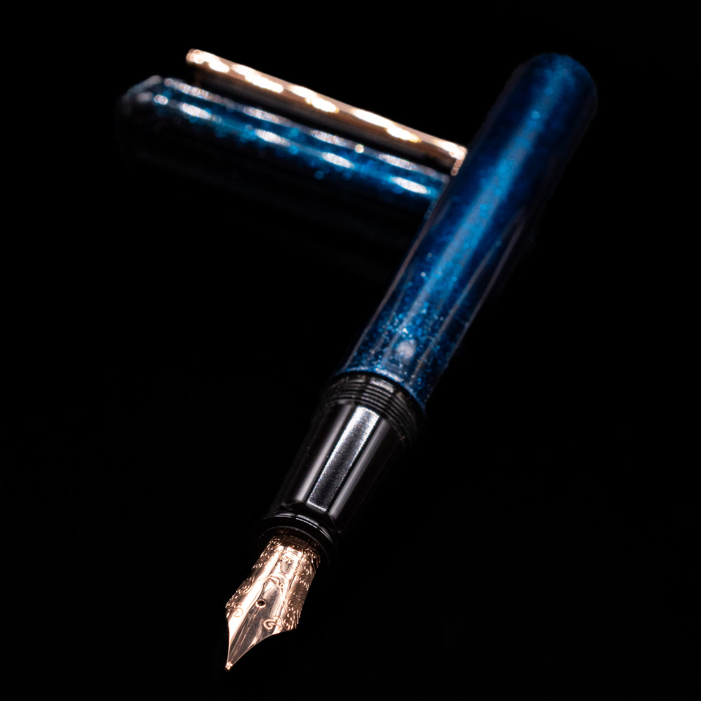Nahvalur Ikkaku Urushi Fountain Pen - Blue Moon laying across its own cap, crossed, with a focus on the nib.