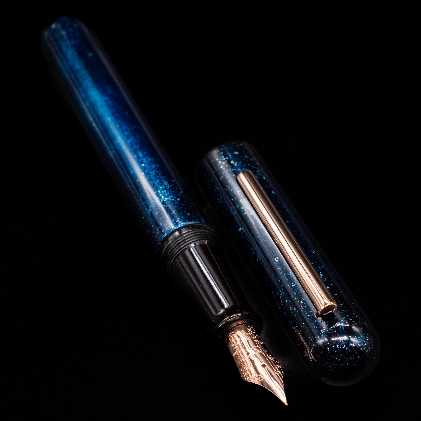 A full view of the Nahvalur Ikkaku Urushi Fountain Pen - Blue Moon uncapped, with its cap laying next to the pen. 
