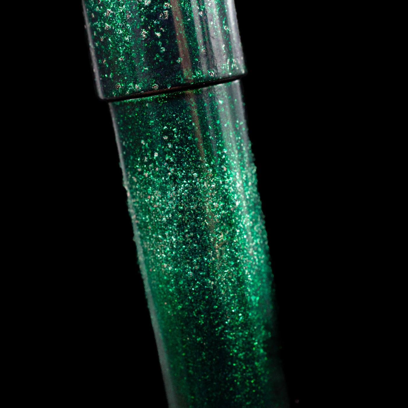A close-up view of the body of the Nahvalur Ikkaku Urushi Fountain Pen - Green Moon showcasing the colorful sparkle details. 