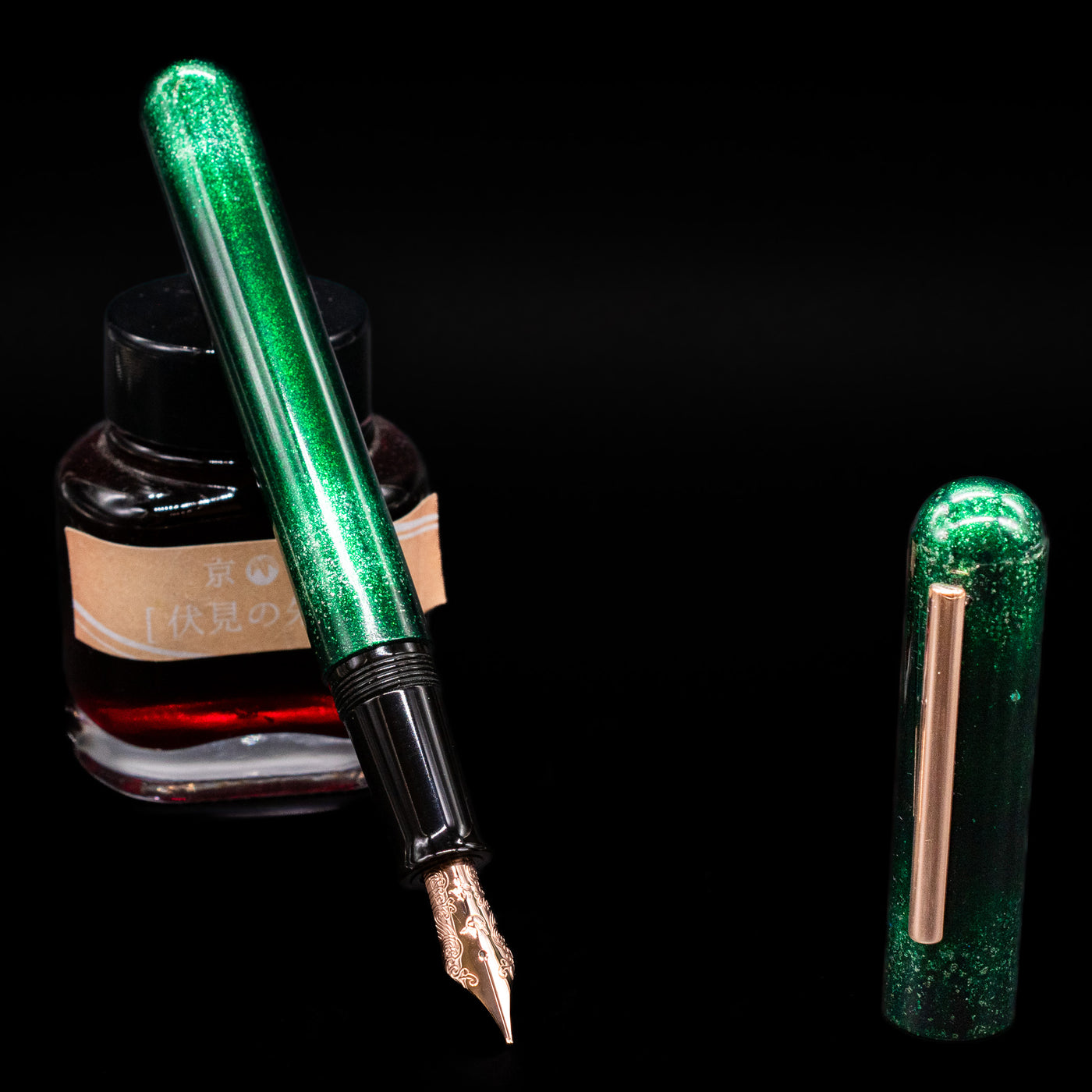 Nahvalur Ikkaku Urushi Fountain Pen - Green Moon leaning on an ink bottle uncapped showcasing the detailing on the nib.