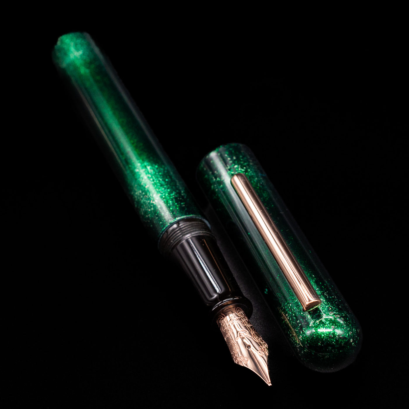 A full view of the Nahvalur Ikkaku Urushi Fountain Pen - Green Moon uncapped, with its cap laying next to the pen. 