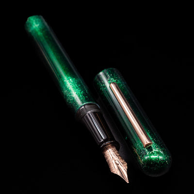 A full view of the Nahvalur Ikkaku Urushi Fountain Pen - Green Moon uncapped, with its cap laying next to the pen. 