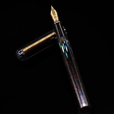 Nahvalur Ikkaku Urushi Fountain Pen - Ye Yu laying on top of its cap in a crossed position showing full view of the entire uncapped pen.