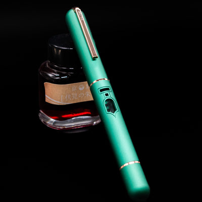 Nahvalur Nautilus Limited Edition Fountain Pen Day 2025 - Emerald capped, leaning on an ink bottle.