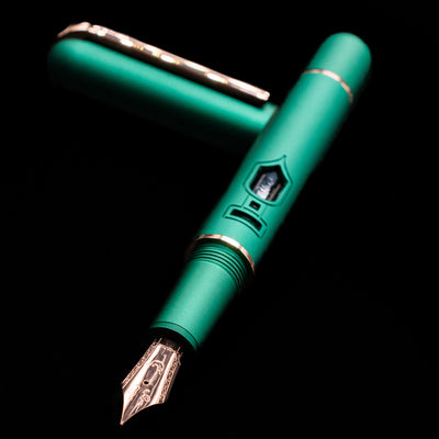 Nahvalur Nautilus Limited Edition Fountain Pen Day 2025 - Emerald laying on top of its cap in a crossed position showing full view of the entire uncapped pen.