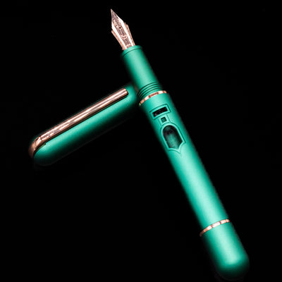 Nahvalur Nautilus Limited Edition Fountain Pen Day 2025 - Emerald laying across its own cap, crossed, with a focus on the nib.