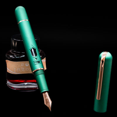 Nahvalur Nautilus Limited Edition Fountain Pen Day 2025 - Emerald  leaning on an ink bottle uncapped showcasing the detailing on the nib.