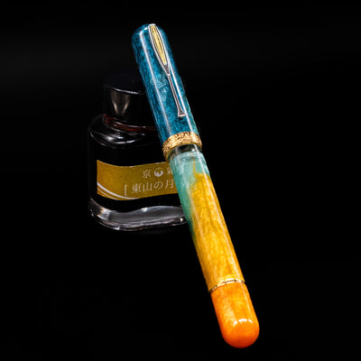 Nahvalur Voyage Fountain Pen - Hawaii capped, leaning against an ink bottle. 