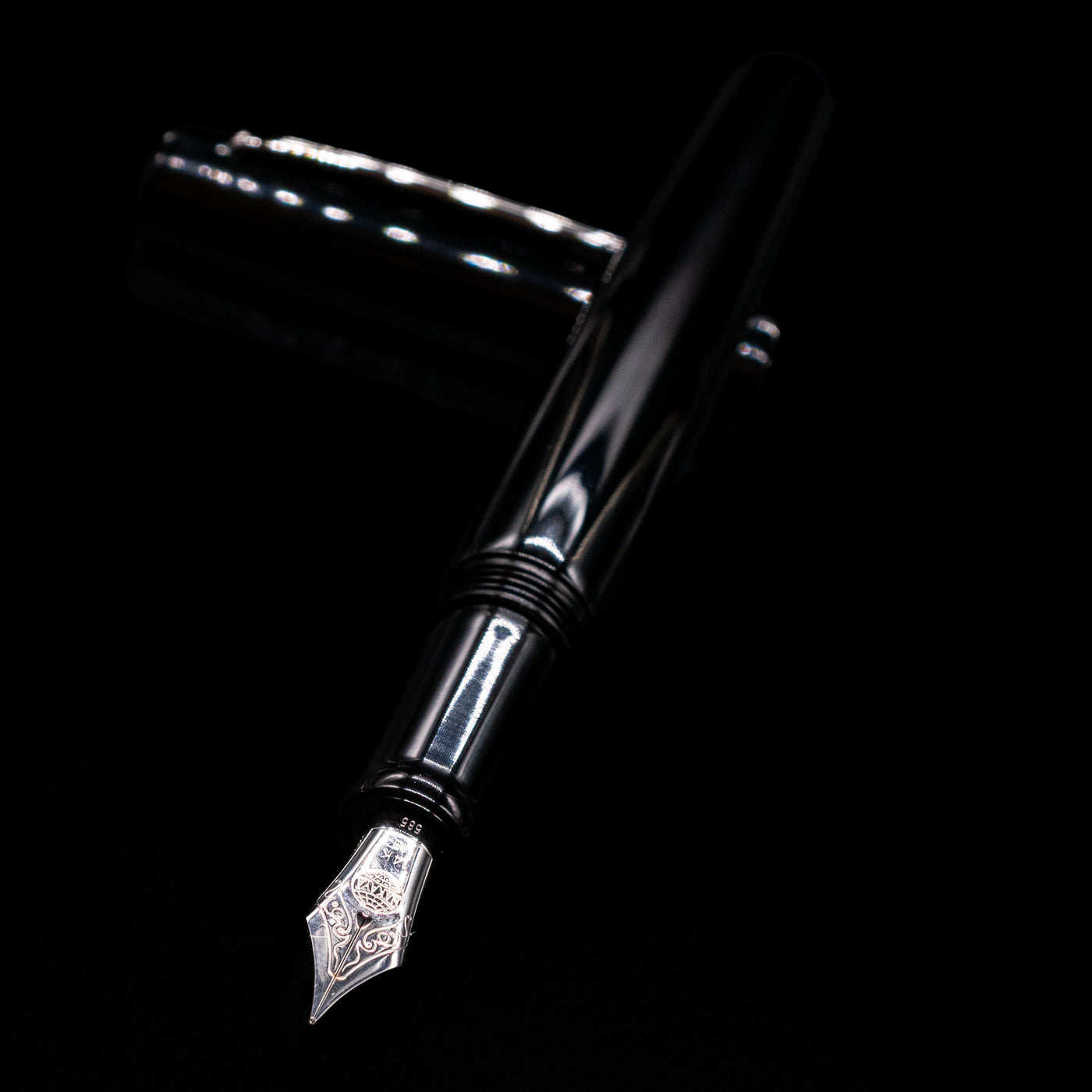 Nakaya Piccola Long Fountain Pen - Kuro Tame laying across its own cap, crossed, with a focus on the nib.