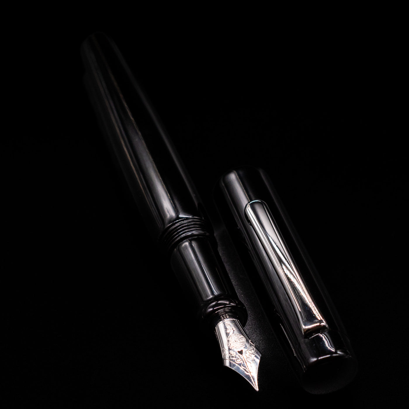A full view of the Nakaya Piccola Long Fountain Pen - Kuro Tame uncapped, with its cap laying next to the pen. 