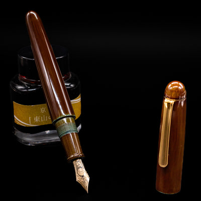 Nakaya Portable Writer Fountain Pen - Heki Tamenuri leaning on an ink bottle uncapped showcasing the detailing on the nib.