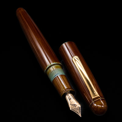 A full view of the Nakaya Portable Writer Fountain Pen - Heki Tamenuri uncapped, with its cap laying next to the pen. 
