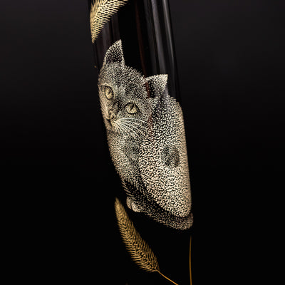 Close-up of cat design in chinkin technique – Highlighting the precise hand-carved gold-inlaid cat motif on deep black urushi lacquer.