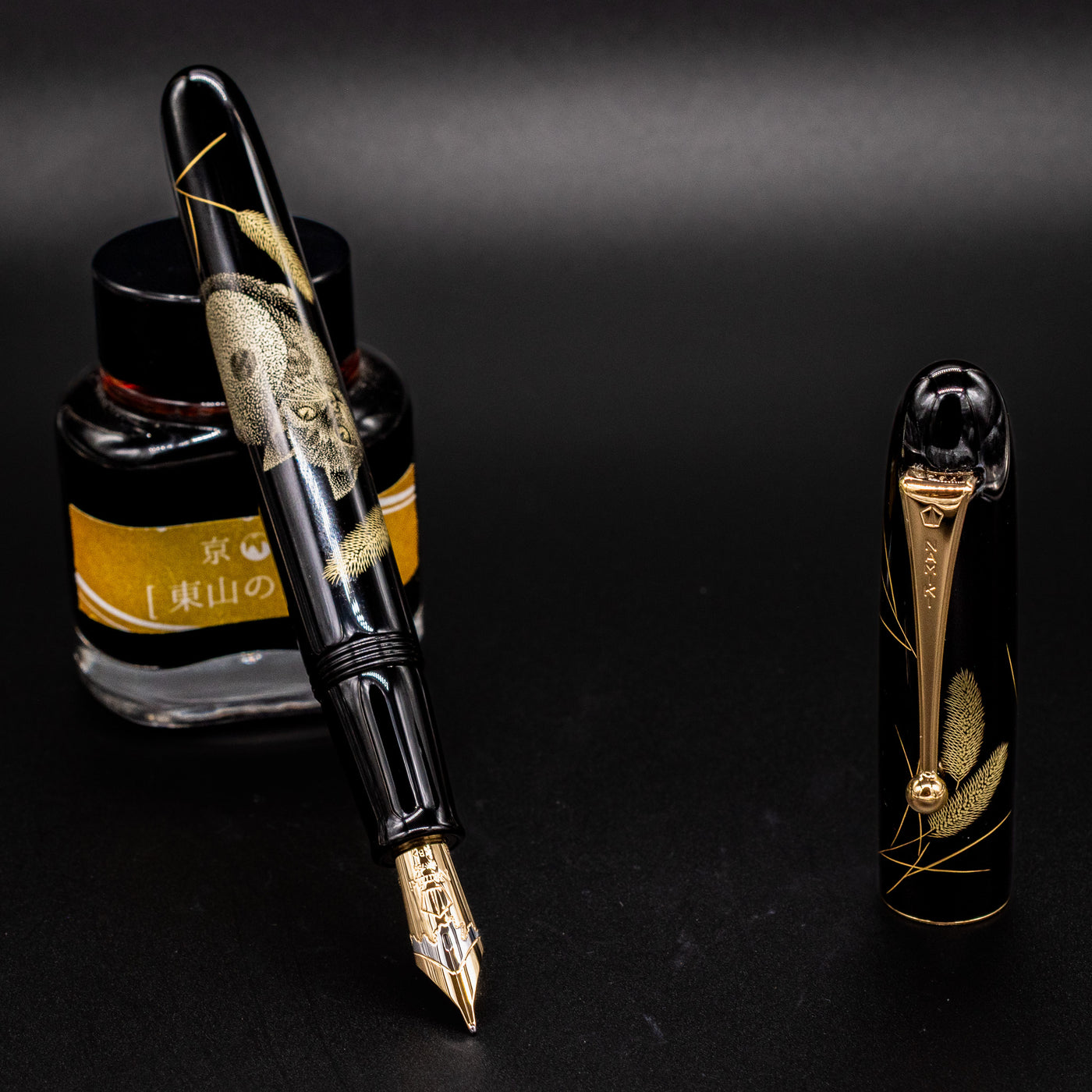 Uncapped Namiki Yukari Royale Cat fountain pen leaning on ink bottle – Showcasing detailed chinkin gold engraving and polished urushi lacquer.