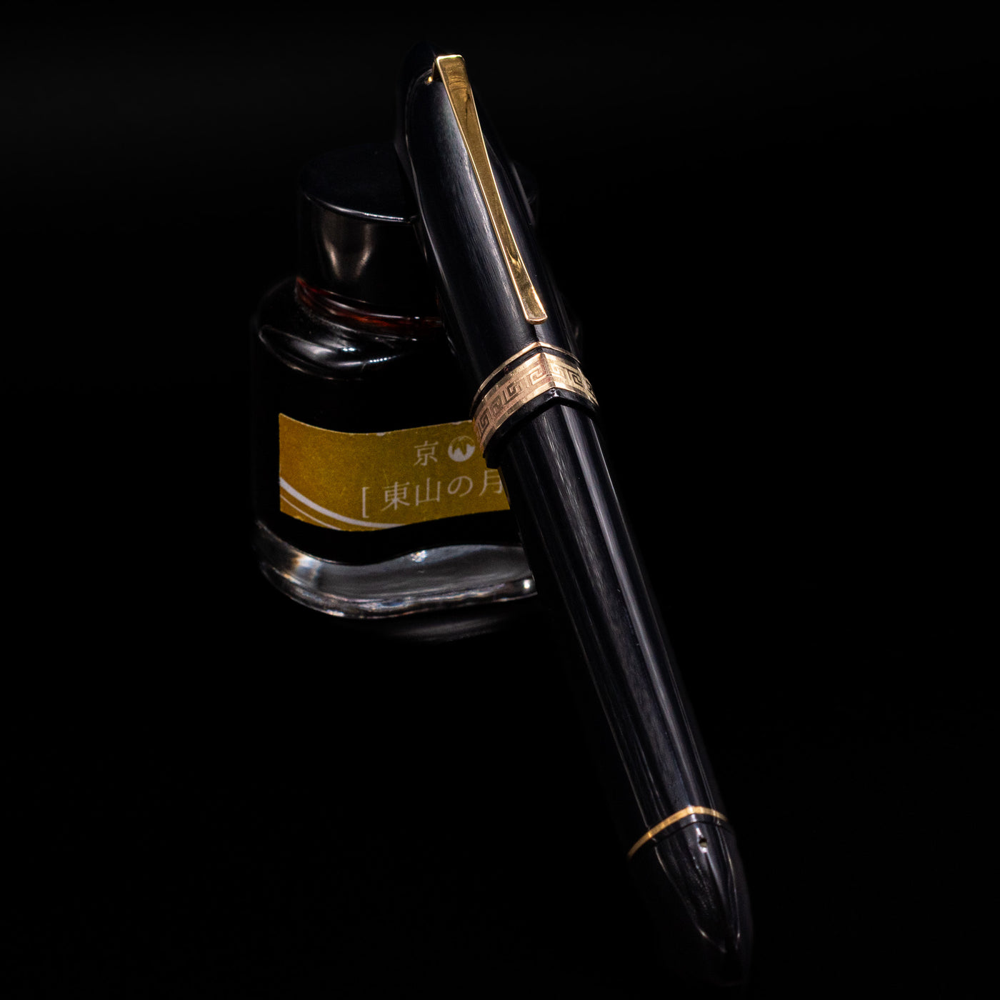 OMAS 360 Dark Blue Fountain Pen - Preowned capped, leaning against an ink bottle. 