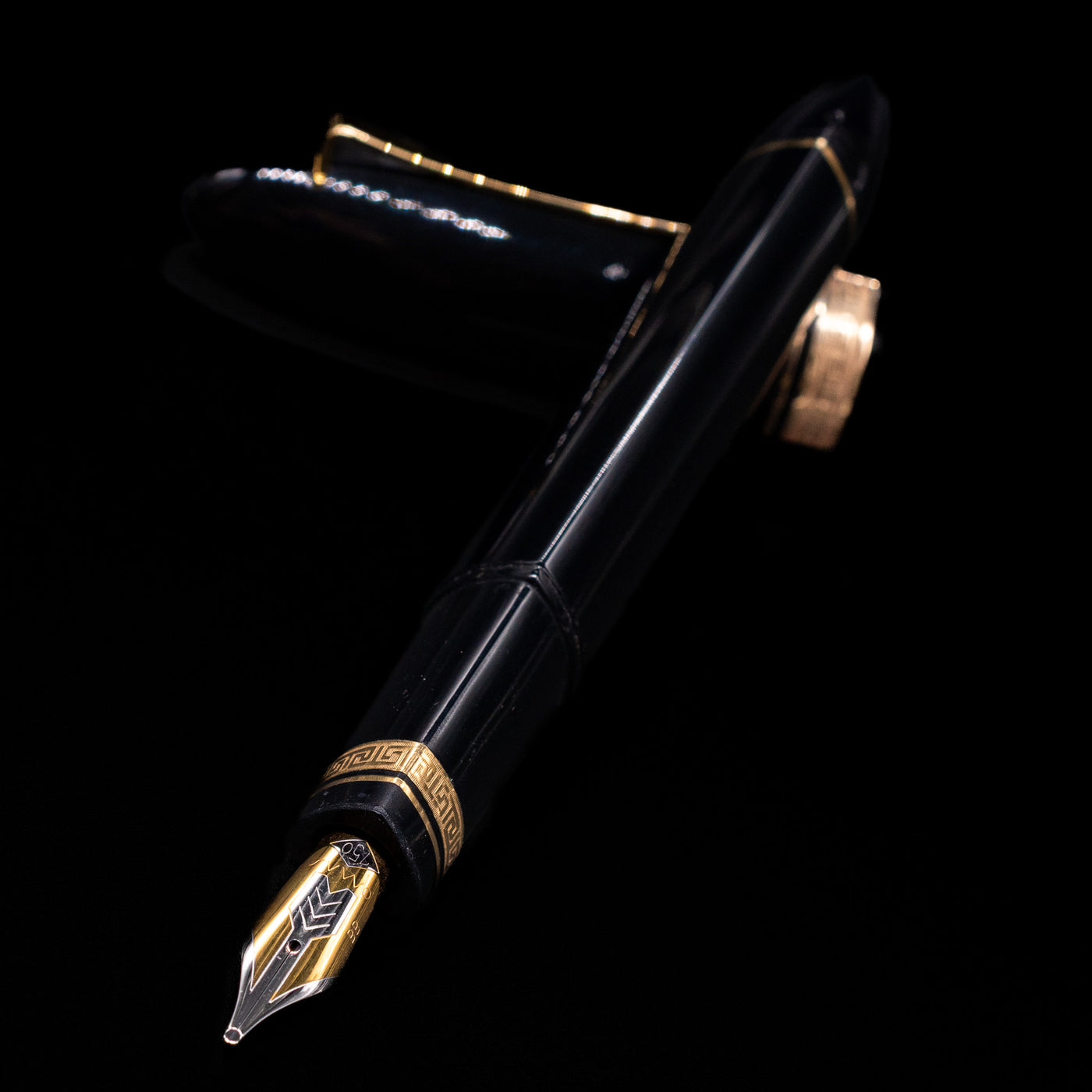 OMAS 360 Dark Blue Fountain Pen - Preowned laying across its own cap, crossed, with a focus on the nib.