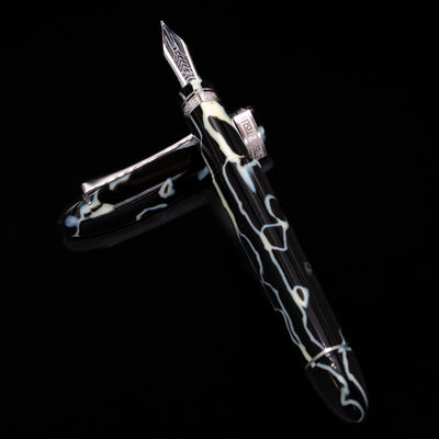 Preowned OMAS 360 Wild Celluloid fountain pen and cap arranged in a crossed position, highlighting the marbled celluloid patterns and the pen’s unique triangular profile.