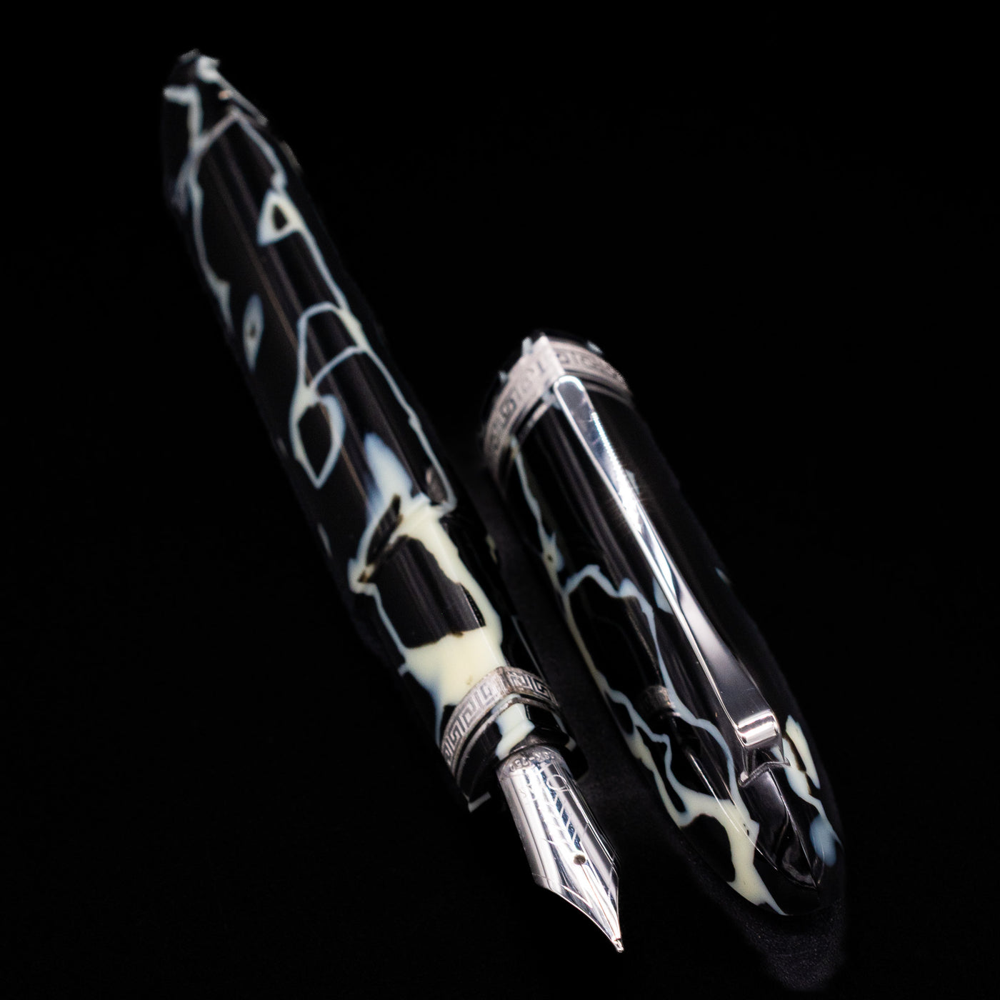 Preowned OMAS 360 Wild Celluloid fountain pen displayed uncapped, showcasing its triangular shape, marbled black and cream celluloid, and gold-plated trim.
