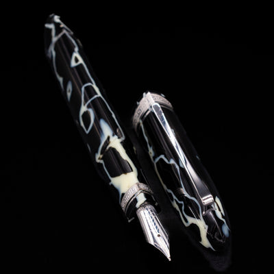 Preowned OMAS 360 Wild Celluloid fountain pen displayed uncapped, showcasing its triangular shape, marbled black and cream celluloid, and gold-plated trim.