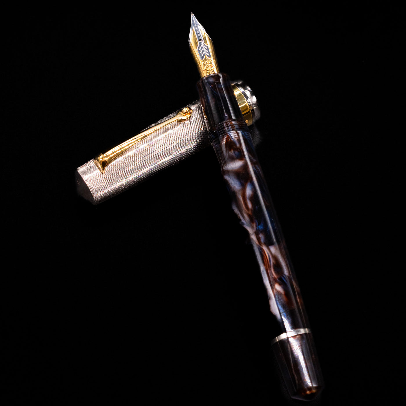 OMAS Bologna Fountain Pen - Galassia Argento laying on top of its cap in a crossed position showing full view of the entire uncapped pen.