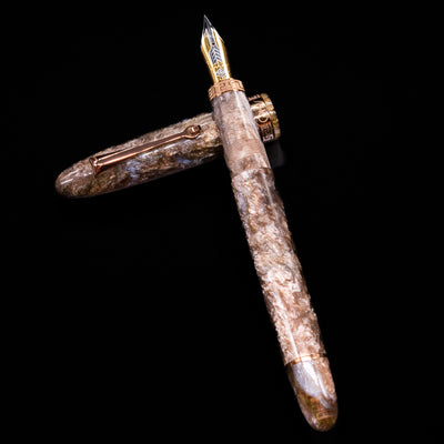 OMAS Ogiva Cocktail Series Fountain Pen - Espresso Martini laying on top of its cap in a crossed position showing full view of the entire uncapped pen.