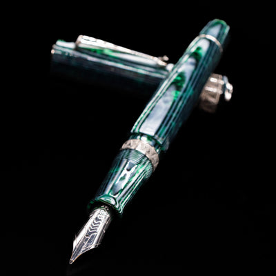 OMAS Paragon Fountain Pen - Arco Verde laying across its own cap, crossed, with a focus on the nib.