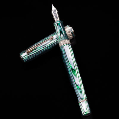 OMAS Paragon Fountain Pen - Arco Verde laying on top of its cap in a crossed position showing full view of the entire uncapped pen.