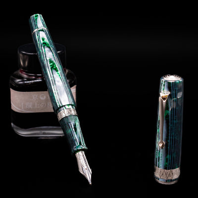 OMAS Paragon Fountain Pen - Arco Verde leaning on an ink bottle uncapped showcasing the detailing on the nib.
