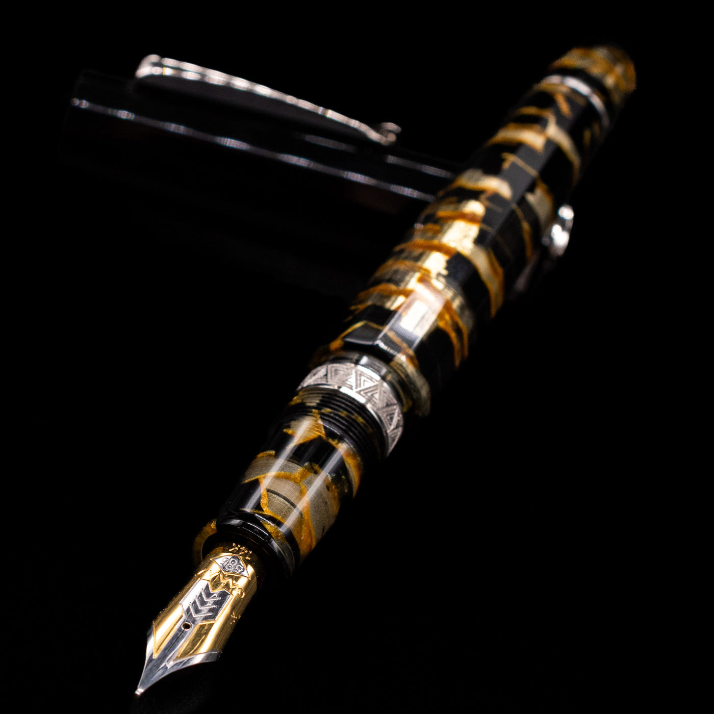 OMAS Paragon Fountain Pen - Black Lucen laying across its own cap, crossed, with a focus on the nib.